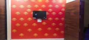 a room with a red wall with a tv on it at Anant home stay in Ujjain