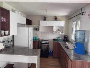 a kitchen with white cabinets and a white refrigerator at Acogedora casita in Guatemala