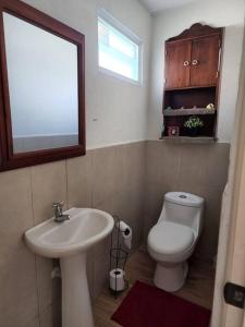 a bathroom with a sink and a toilet and a mirror at Acogedora casita in Guatemala +7 photos