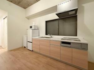 a kitchen with a sink and a refrigerator at b hotel NaouBLD - Central Hatchobori 2 Bedroom Apartment for 10 Guests in Hiroshima