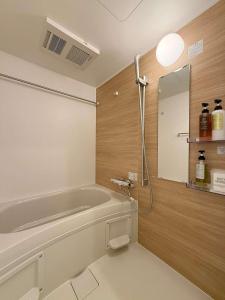 a bathroom with a bath tub and a mirror at b hotel NaouBLD - Central Hatchobori 2 Bedroom Apartment for 10 Guests in Hiroshima +20 photos