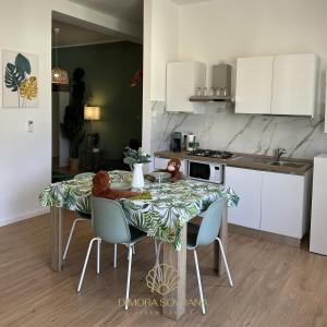 a kitchen with a table with chairs and a kitchen with white cabinets at Dimora Sovrana - Urban Jungle in Matera +37 photos