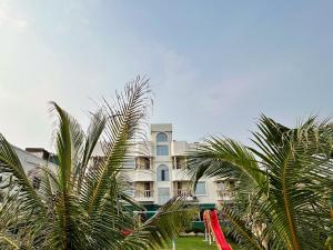 a large building with palm trees in front of it at Sunview Resort in Mandarmoni