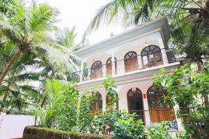 a large house with a balcony and palm trees at Peaceful Rooms at Pande Residency in Patnem