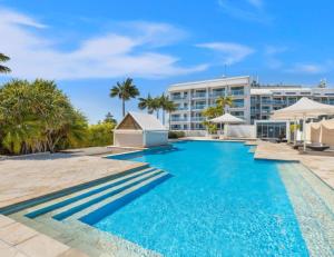 a swimming pool with a hotel in the background at The Entrance Waterfront Resort, Unit 614 in The Entrance