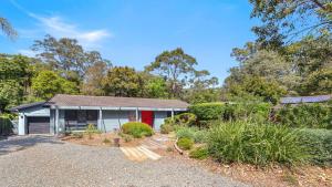 ein Haus mit einer roten Tür im Garten in der Unterkunft Opal Oasis in Pearl Beach + 11 Fotos