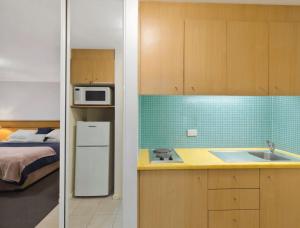 a small kitchen with a sink and a bed at The Entrance Waterfront Resort, Unit 614 in The Entrance