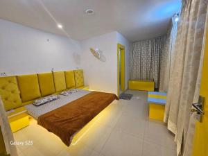 1 dormitorio con 1 cama grande y cabecero amarillo en The OrtusStays - Sunrise Room, en Orchha