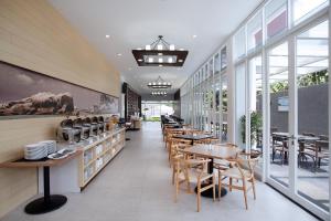 a restaurant with tables and chairs and windows at DK Belstar Hotel Belitung in Tanjungpandan