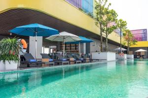 a swimming pool with chairs and umbrellas next to a building at Flamingo Ibiza Hai Tien managed by Flamingo Hotels and Resorts in Nam Khê