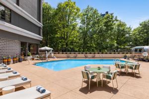 a pool with tables and chairs next to a building at The American Hotel Atlanta Downtown, Tapestry Collection by Hilton in Atlanta