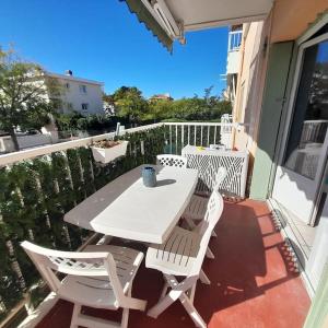 a white table and chairs sitting on a balcony at Petit Coin de Paradis 2 MN de la mer 2chs balcon clim parking in Six-Fours-les-Plages