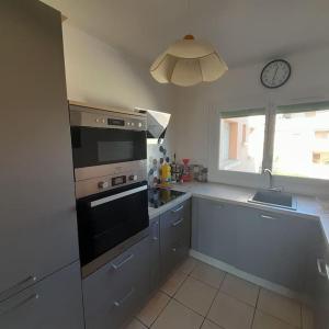 a kitchen with a stove and a window with a clock at Petit Coin de Paradis 2 MN de la mer 2chs balcon clim parking in Six-Fours-les-Plages