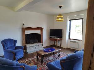 a living room with blue chairs and a fireplace at Maison du Moulin in Maen Roch
