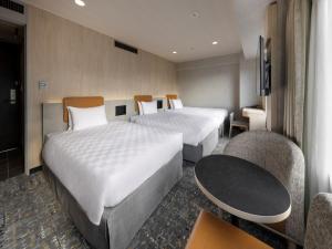 a hotel room with two beds and a table and chairs at Shinjuku Prince Hotel in Tokyo
