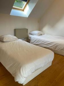 two white beds in a room with a skylight at Maison du Moulin in Maen Roch