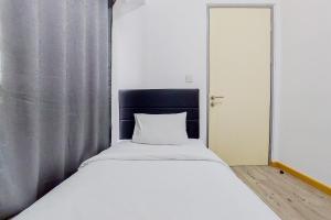 a white bed with a black headboard in a room at Nice 2BR Apartment at M-Town Residence By Travelio in Tangerang +12 photos
