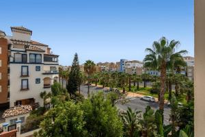 Blick auf eine Straße mit Palmen und Gebäuden in der Unterkunft Marina III PLUS by Ĥ - Marina Isla Canela PMHIII6P18 in Punta del moral