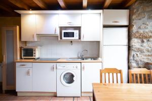 a kitchen with white cabinets and a washing machine at Errotazar apartamento rural K in Alsasua