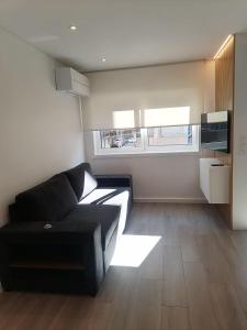 ein Wohnzimmer mit einem schwarzen Sofa und einem Fenster in der Unterkunft Beach House in Póvoa de Varzim