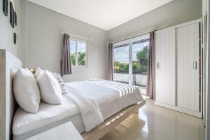une chambre blanche avec un grand lit et une fenêtre dans l'établissement De Gani, à Seminyak 52 autres photos