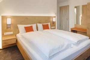 a large bed with white sheets and orange pillows at Landhotel Steigenhaus in Untermünkheim +24 photos