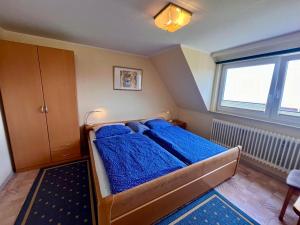 a bedroom with a bed with blue sheets and a window at Ferienwohnung Janssen in Borkum