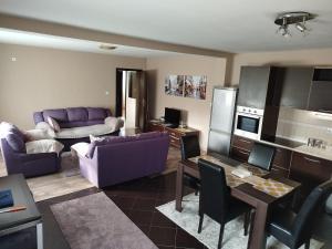 a living room with purple furniture and a kitchen at Apartment Filipovic in Podgorica