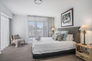 una camera da letto con un letto grande e una sedia di Byron Marvel - Luxury Byron Bay Penthouse Holiday Rental with Balcony, 4 Bedrooms, Sleeps 10 a Byron Bay