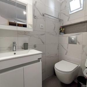 a white bathroom with a toilet and a sink at Nefeli Luxury Studios in Kamena Vourla