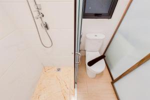 a small bathroom with a toilet and a shower at Spacious and Comfortable 2BR at Sky House BSD Apartment By Travelio in Tangerang +11 photos