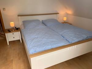 a bed with blue sheets and two lamps on two tables at Haus Petra in Borkum
