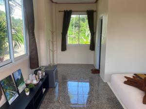 Una sala de estar con un sofá y dos ventanas. en Arya Bungalow, en Phra Ae beach