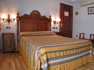 a bedroom with a large bed with a wooden headboard at Hotel del Pastor in Morella
