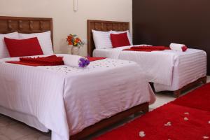a bedroom with three beds with red and white sheets at White Peacock Resort Mtwapa in Mombasa