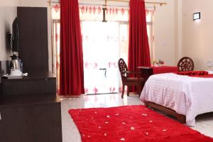 a bedroom with a bed with red curtains and a red rug at White Peacock Resort Mtwapa in Mombasa