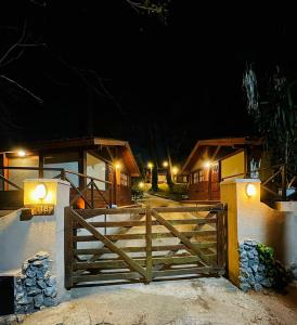a wooden fence in front of a house at night at Cabañas Entre Pinos in Villa Gesell