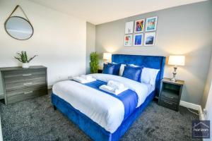 a bedroom with a blue bed and a mirror at Dalkeith House By Horizon Stays in Hartlepool +14 photos