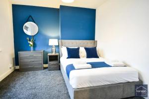 a blue bedroom with a bed and a mirror at Dalkeith House By Horizon Stays in Hartlepool