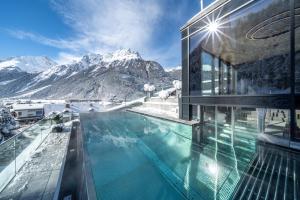 a house with a swimming pool in front of a mountain at Hotel Stern in Längenfeld