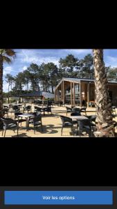 a group of tables and chairs in front of a building at Les dunes de Contis Chez Edith océan pins et détente assurée dans camping 4 étoiles in Saint-Julien-en-Born