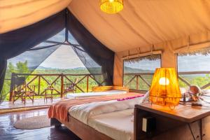 a bedroom with a bed and a table with a lamp at Rhotia Valley Tented camp in Karatu
