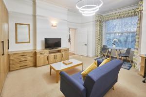 een woonkamer met een blauwe bank en een tv bij Host & Stay - Thamesview in Staines