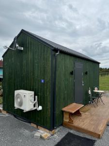 a green building with a fan and a wooden deck at Tiny Haus im Quittengarten in Distelhausen