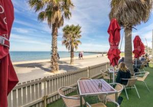 una mujer sentada en una mesa cerca de la playa en Elwood stylish apartment in botanical location near beach, en Melbourne