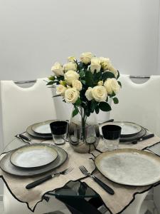 a table with plates and a vase of white roses at Studio 36mt2 a 5 min a pied boulevard de Belgique MC in Beausoleil