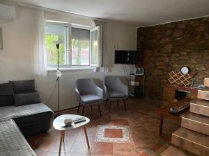 a living room with a couch and chairs and a stone wall at Vila Vera Novosadska 15 in Velika Remeta