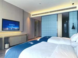 a bedroom with a large bed and a flat screen tv at Echarm Hotel Nanchong Taihe Center Nanchong Railway Station in Nanchong
