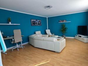 a living room with a white couch and blue walls at Ferienwohnung Freedom 2 Sky Terrasse High End in Northeim