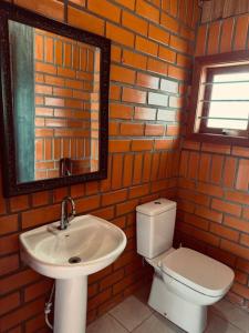 a bathroom with a sink and a toilet and a mirror at Oliveira montain House in Tijucas